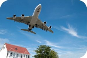 large plane in blue sky flying very closely over a home for funny customer service stories