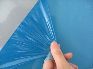 hand peeling blue plastic film being peeled off flat surface for funny customer service stories